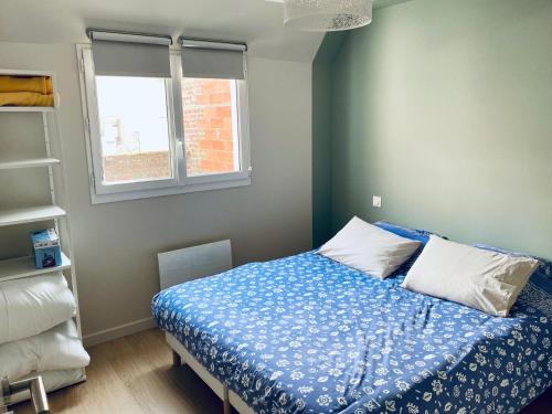 une chambre avec un lit avec des draps bleus et une fenêtre dans l'établissement Fernand - Maison centre ville - cour extérieure - Le Touquet, à Le Touquet-Paris-Plage