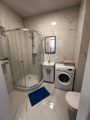 a bathroom with a shower and a washing machine at A63 by Real Apartment in Warsaw