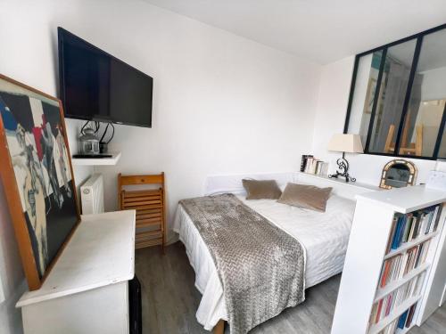 une chambre avec un lit et une télévision à écran plat dans l'établissement Studio cosy près de Paris et de l'Aéroport CDG, à Drancy