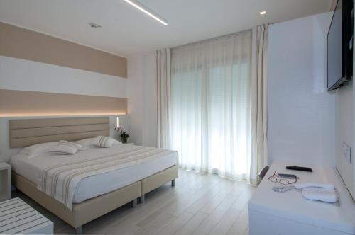a white bedroom with a bed and a window at Lungomare Relax Residence in Misano Adriatico