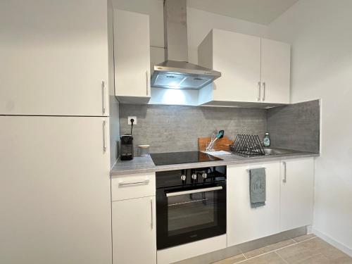 une cuisine avec des armoires blanches et un four à plaques de cuisson dans l'établissement Calvi - Paisible et chaleureux, à Reims