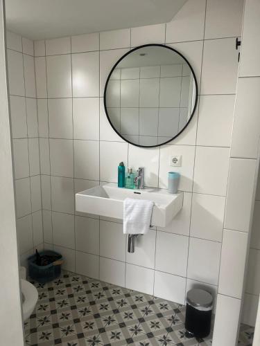 a white tiled bathroom with a sink and a mirror at Het Doktershuys in Gieten