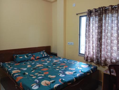 a bedroom with a bed with a blue comforter and a window at Rukmini Guest House in Kolkata