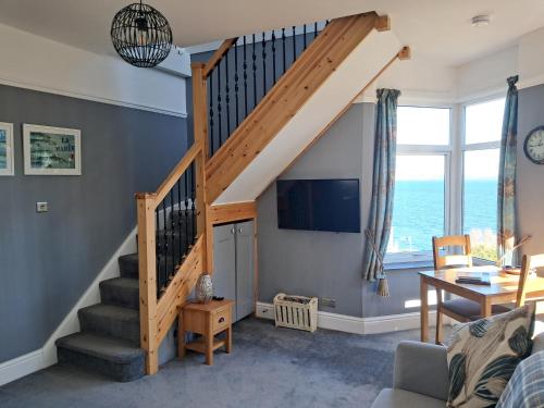 a living room with a staircase with a tv at Eddystone Light Apartment in Mevagissey
