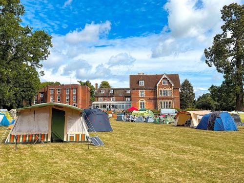 a group of tents in a field in front of a building at Comfortable Double Room with Bath in Cranleigh