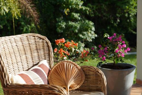 2 Korbstühle auf einer Terrasse mit Blumen in der Unterkunft Palsona Maison Remissis in Sainte-Luce