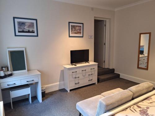 a living room with a couch and a tv and a mirror at Comfortable Spacious Double Ensuite Room in Cranleigh