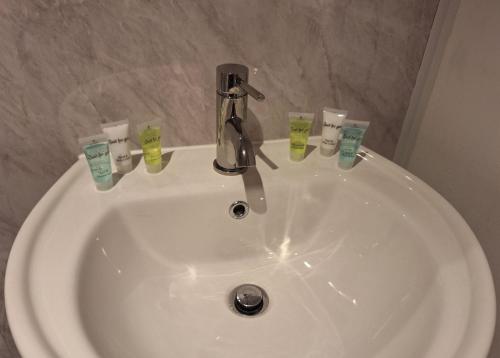 a white sink with toothbrushes and a faucet at Comfortable Spacious Double Ensuite Room in Cranleigh