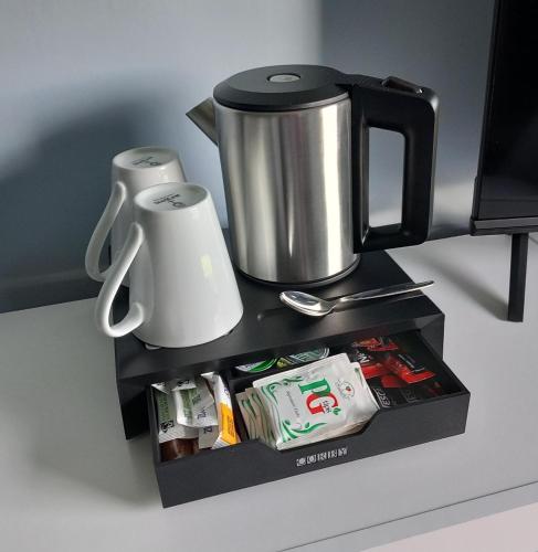 a coffee station with a coffee pot and cups at Comfortable Spacious Double Ensuite Room in Cranleigh