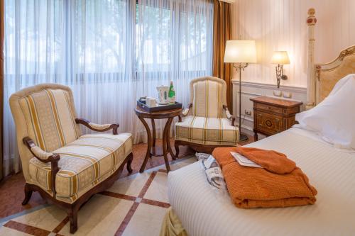 a bedroom with two beds and two chairs and a table at Mercure Petriolo Siena Terme Spa Hotel in Bagni di Petriolo
