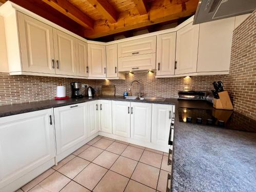 une cuisine avec des armoires blanches et un sol carrelé dans l'établissement Chalet Alpin au calme avec WIFI et parking à Samoëns - FR-1-624-10, à Samoëns