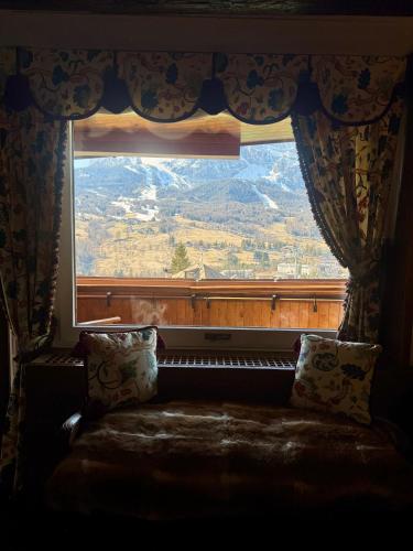 a window with a couch looking out at a mountain at Elegant Apartment with center and Tofana view in Cortina dʼAmpezzo