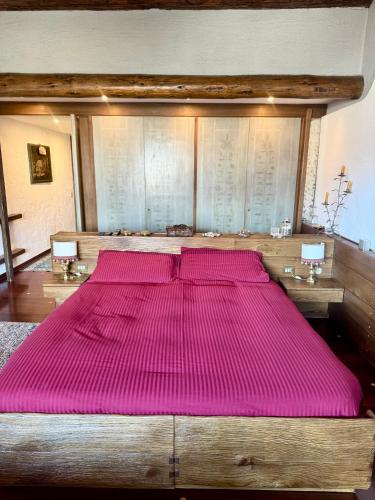 a large wooden bed with pink sheets in a room at Elegant Apartment with center and Tofana view in Cortina dʼAmpezzo