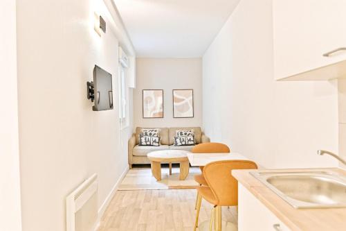 un salon blanc avec un canapé et une table dans l'établissement Cozy and convenient studio in Asnières-sur-Seine-V, à Asnières-sur-Seine