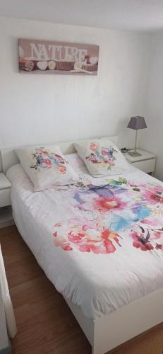 - un lit blanc orné de fleurs dans la chambre dans l'établissement ISIS 2 Joli duplex proche plage et port - CLIM PARKING LOGGIA ET BALCON, à Saint-Cyprien