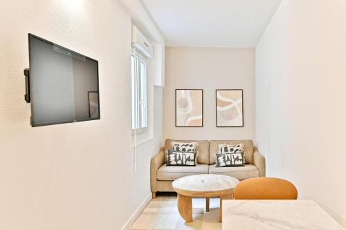un salon avec un canapé et une télévision sur un mur dans l'établissement Cozy and convenient studio in Asnières-sur-Seine-V, à Asnières-sur-Seine