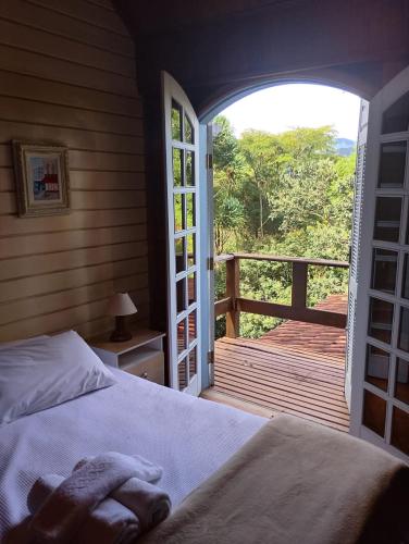 a bedroom with a bed and a view of a deck at Pássaro de Fogo in Santo Antônio do Pinhal