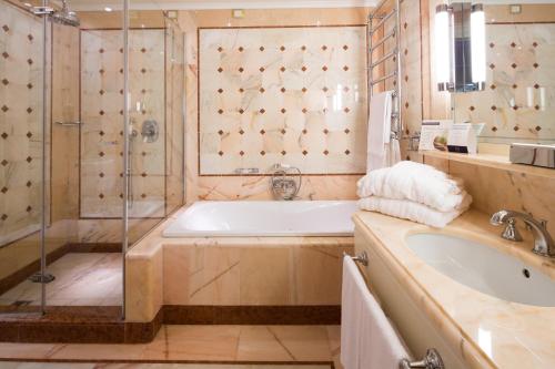 a bathroom with a tub and a shower and a sink at Mercure Petriolo Siena Terme Spa Hotel in Bagni di Petriolo