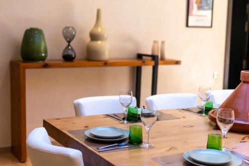a wooden table with plates and wine glasses on it at Villa Anna - Havre de paix in Oulad Ikhia