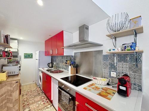 La cuisine est équipée de placards rouges et d'un four avec plaques de cuisson. dans l'établissement SUNNY Duplex classé 3 etoiles climatisé à 2mn à pieds du Port byLaConciergerie13, à La Ciotat