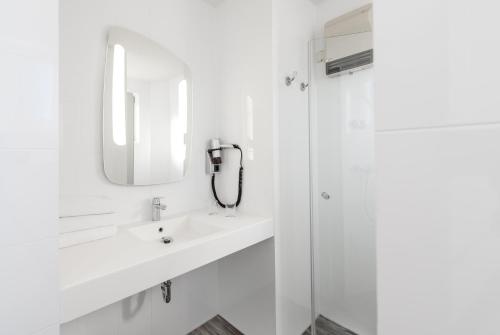 a white bathroom with a sink and a mirror at ibis Frankfurt Centrum in Frankfurt/Main