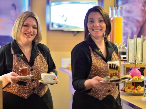 two women holding plates of food and a cup of coffee at Prinzhotel Rothenburg in Rothenburg ob der Tauber