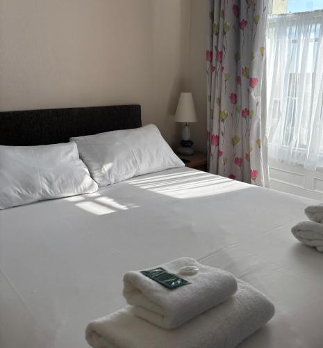 a white bed with towels and a remote control on it at Carnock in Tenby