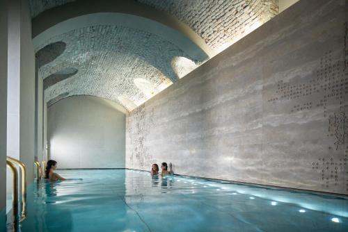 a swimming pool with three people in the water at Four Seasons Hotel Milano in Milan