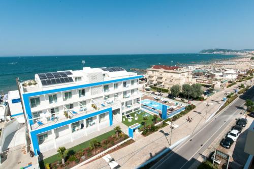 a large white building with a swimming pool next to the ocean at Lungomare Relax Residence in Misano Adriatico