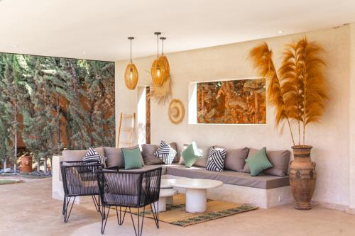 a living room with a couch and a table and chairs at Villa Anna - Havre de paix in Oulad Ikhia