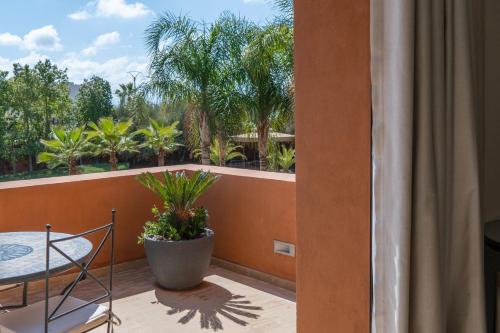 a balcony with a table and a view of palm trees at Villa Anna - Havre de paix in Oulad Ikhia