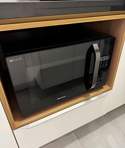 a microwave oven with a black door in a cabinet at Aquarius Residence by Holiday Stays in Fortaleza