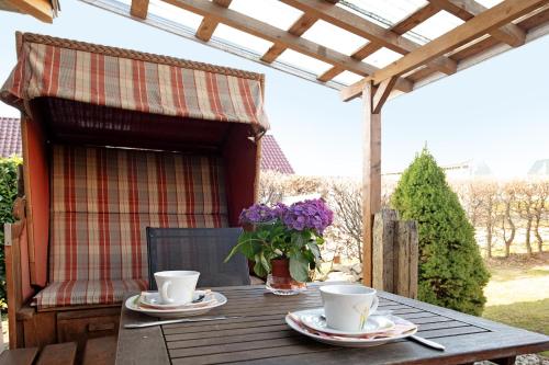 a wooden table with two cups and a vase of flowers at Ferienwohnung 'an der Ostsee' in Mechelsdorf