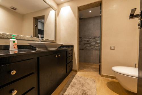 a bathroom with a sink and a toilet and a mirror at Villa Anna - Havre de paix in Oulad Ikhia