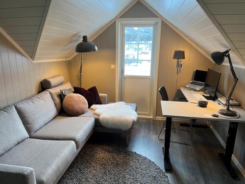 a living room with a couch and a desk with a computer at Scenic Private House Surrounded by Nature in Sæbø