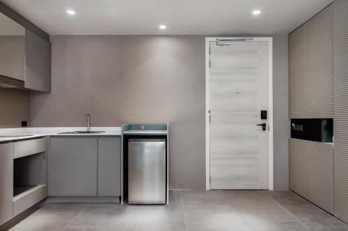 a kitchen with a stainless steel refrigerator and a door at Bayphere Hotel Pattaya JC in Na Jomtien