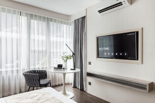 a hotel room with a table and a tv at Bayphere Hotel Pattaya JC in Na Jomtien