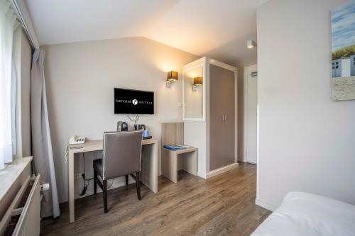 a room with a desk with a computer and a tv at Fletcher Zuiderduin Beachhotel in Westkapelle