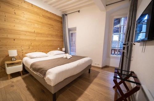 une chambre avec un grand lit avec un mur en bois dans l'établissement Hyper Centre Proche Gare Sauna Balcon, à Annecy