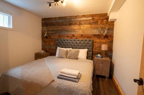 a bedroom with a bed with a wooden accent wall at Carriole - Private Hot Tub - Hiking and Skiing in Val-des-Lacs