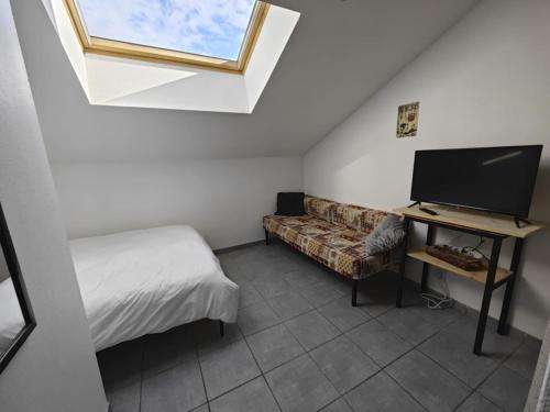 a bedroom with a bed and a tv and a couch at Serre Chevalier 2 pièces à 150 m du télécabine Prorel in Briançon