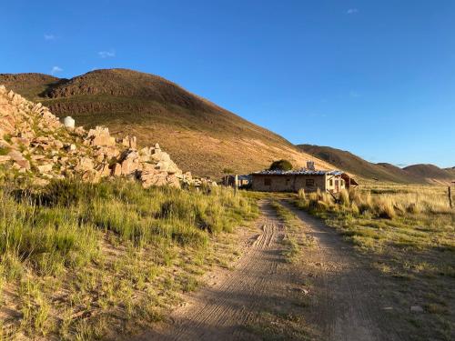 a dirt road in a field with a hill at Cabaña huasi rumi in Abra Pampa