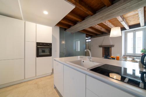 Una cocina con gabinetes blancos y un fregadero. en Duomo Apartment, en Iseo