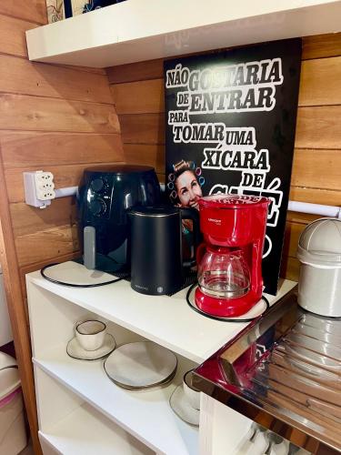 a shelf with a coffee maker on it in a kitchen at Chalé Barril com cozinha in São Francisco do Sul