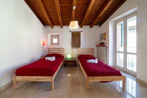 two beds in a room with red sheets at Duomo Apartment in Iseo