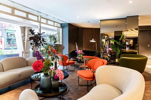 a lobby with couches and chairs and flowers at NH Collection Amsterdam Flower Market in Amsterdam