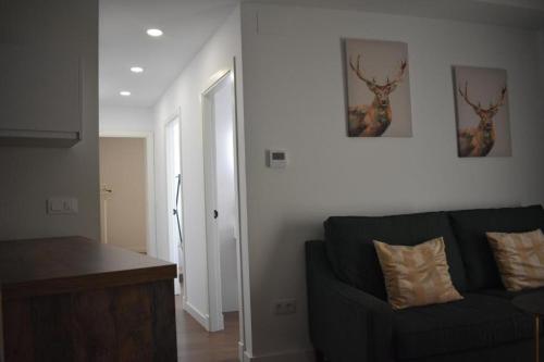 a living room with a black couch and two pictures on the wall at Apartamentos Molinos in Constantina