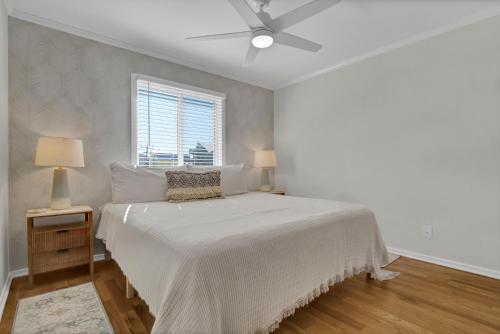 a white bedroom with a bed and a ceiling fan at After Dune Delight by Sea Scape Properties in Carolina Beach