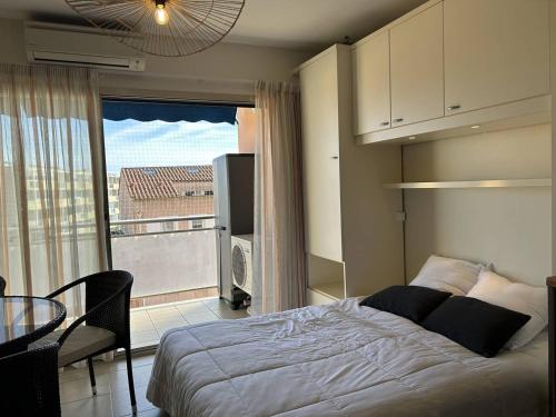 - une chambre avec un lit, une table et un balcon dans l'établissement Studio cabine climatisé avec terrasse au centre-ville - 4 couchages - Le Lavandou - FR-1-251-723, au Lavandou