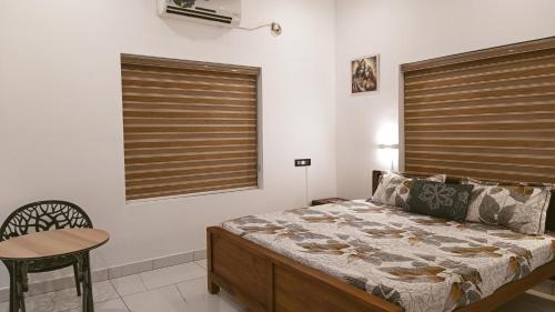 a bedroom with a bed and a table and a chair at Cliff Aura by Saash Hotels in Varkala